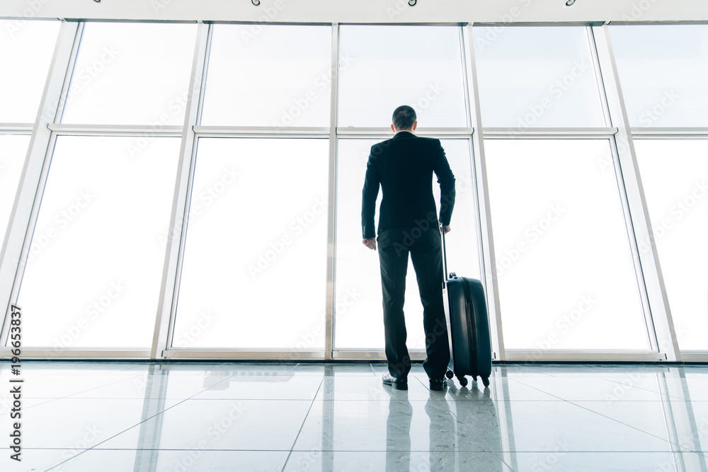 Business man at airport with suitcase waiting for departure near gate. Business travel Business man at airport with suitcase waiting for departure near gate. Business travel