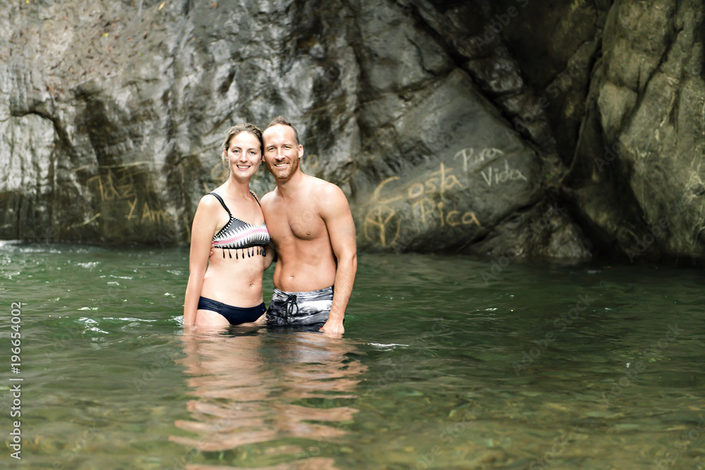 Fototapeta premium Attractive couple under jungle waterfall