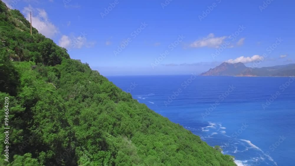 Paradise island aerial shot - beautiful landscape. Camera flying over a forest, with deep blue sea in the background Paradise island aerial shot - beautiful landscape. Camera flying over a forest, with deep blue sea in the background
