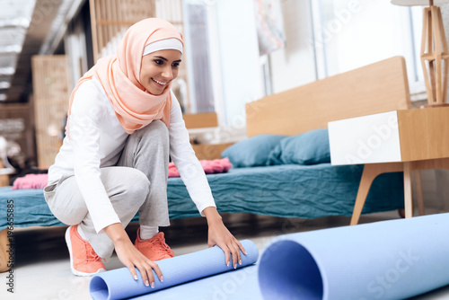 Arab woman preparing a mat to do gymnastics in the bedroom.