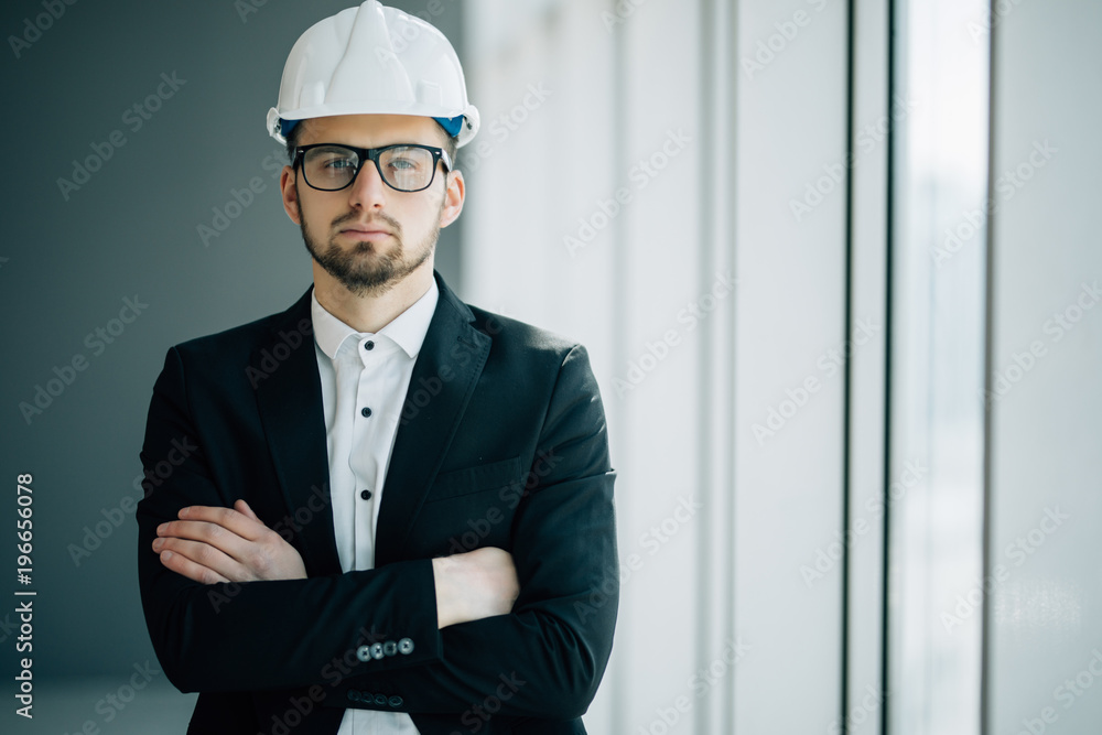 Successful engineer or architect, Joyous businessman with crossed arms wearing helmet on office building background Successful engineer or architect, Joyous businessman with crossed arms wearing helmet on office building background