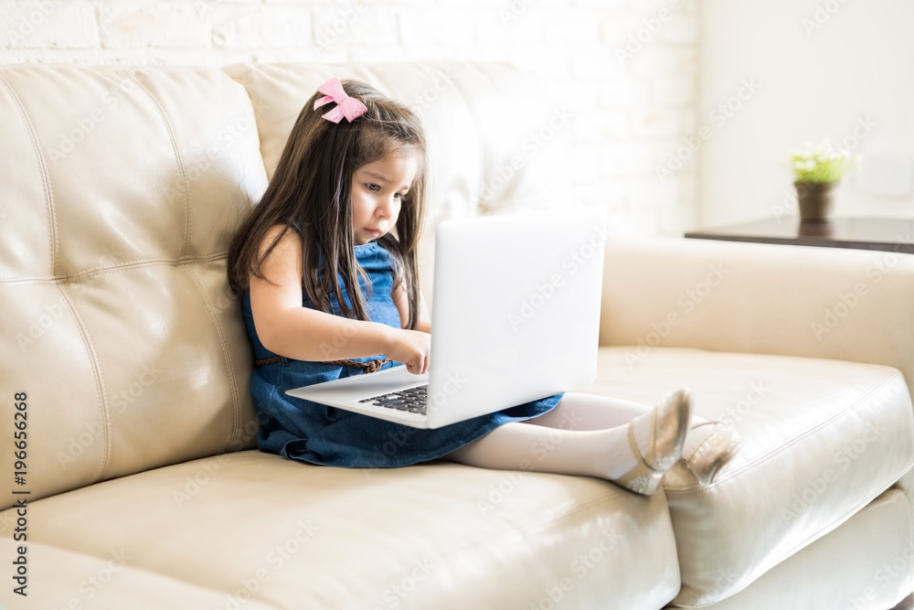 Cute little girl using a laptop at home Cute little girl using a laptop at home