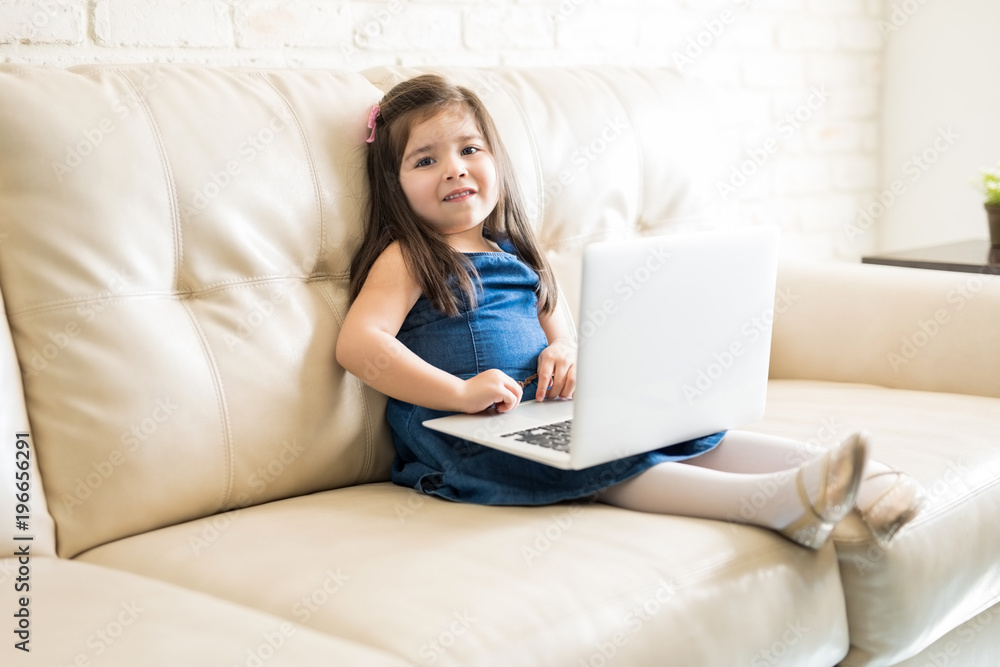Cite little girl with laptop in living room