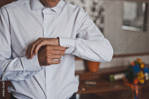 Mens hands fasten the sleeve of a snow-white shirt 792.