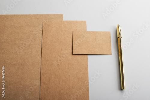 Top view of cardboards, business card in brown and golden ballpoint pen on gray background. Mockup. © Freestocker
