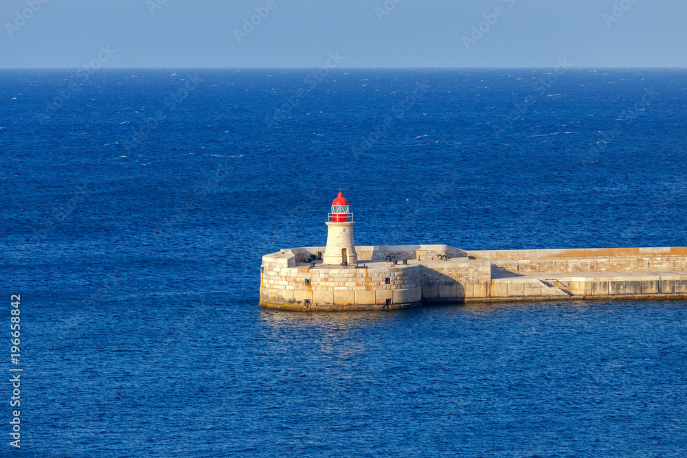 Valletta. A lighthouse and a breakwater at the entrance to the harbor.