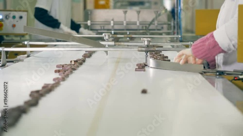 Chocolate bars are slowly moving along the conveyor belt after being sorted by workers photo