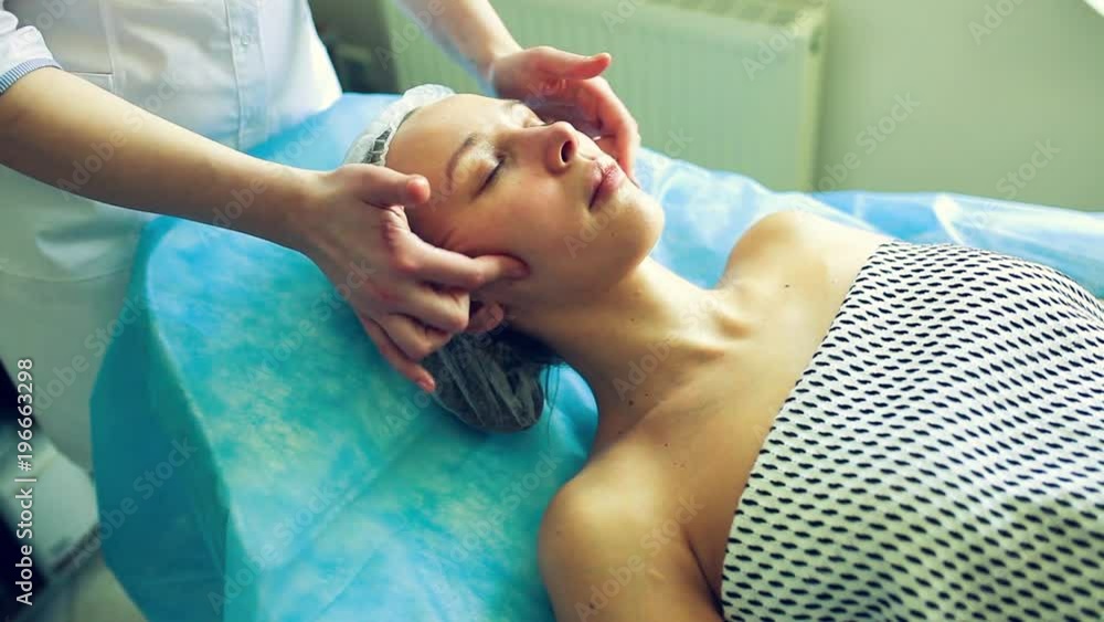 A beautician woman does face massage to a patient A beautician woman does face massage to a patient