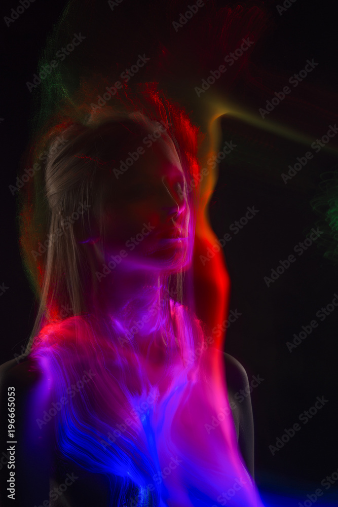 Conceptual avant-garde silhouette portrait of a beautiful blonde girl covered with multicolored lines applied by a lightbrush