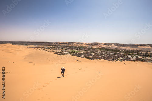 Tahgit - June 06, 2017: Western traveler climbing a dune in Taghit, Algeria