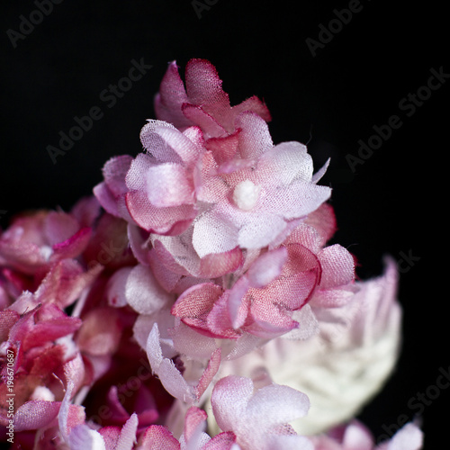 Pink lilacs on a black background. Artificial flowers