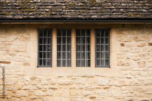 Closeup of yellow and gray stone wall with window and roof for background.