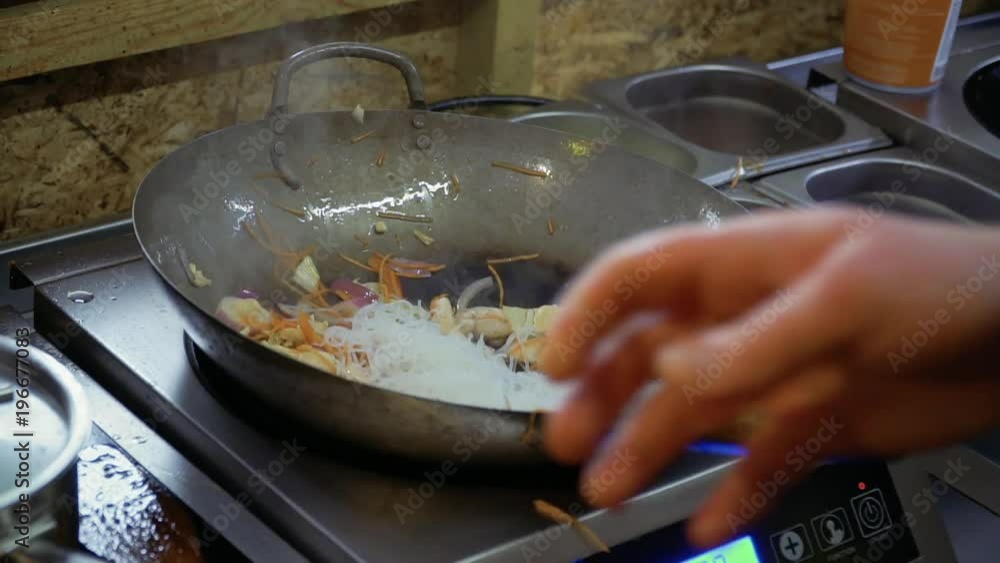 Chef put rice noodles into a hot pan with fried vegetables Chef put rice noodles into a hot pan with fried vegetables