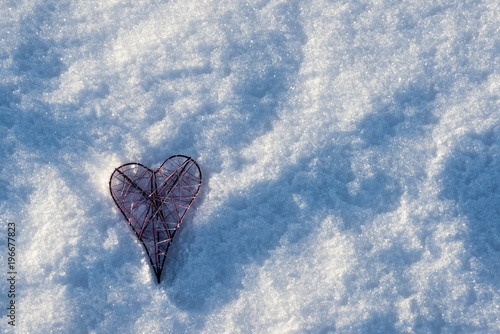 Metal pink heart lying in the snow with copy spave for banner or background photo