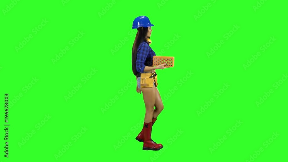Girl in the helmet bears the brick side view on a green background Girl in the helmet bears the brick side view on a green background