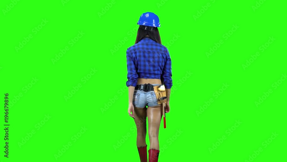 Rear view of girl wearing helmet and shorts walking on green background