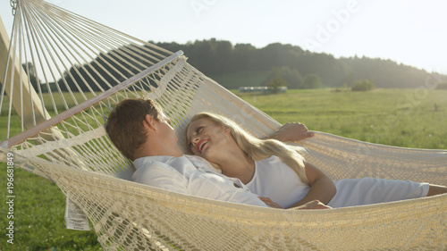 CLOSE UP: Cheerful couple lovingly looking into each other's eyes while relaxing