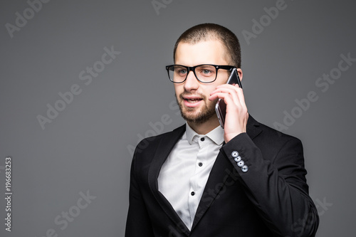 Portrait of casual businessman talking on mobile phone isolated on gray