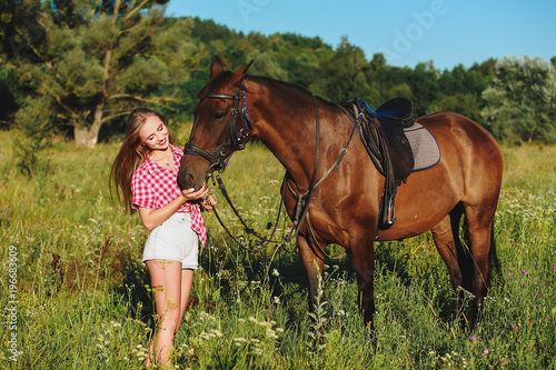 Beautiful blonde girl with a horse in the field.