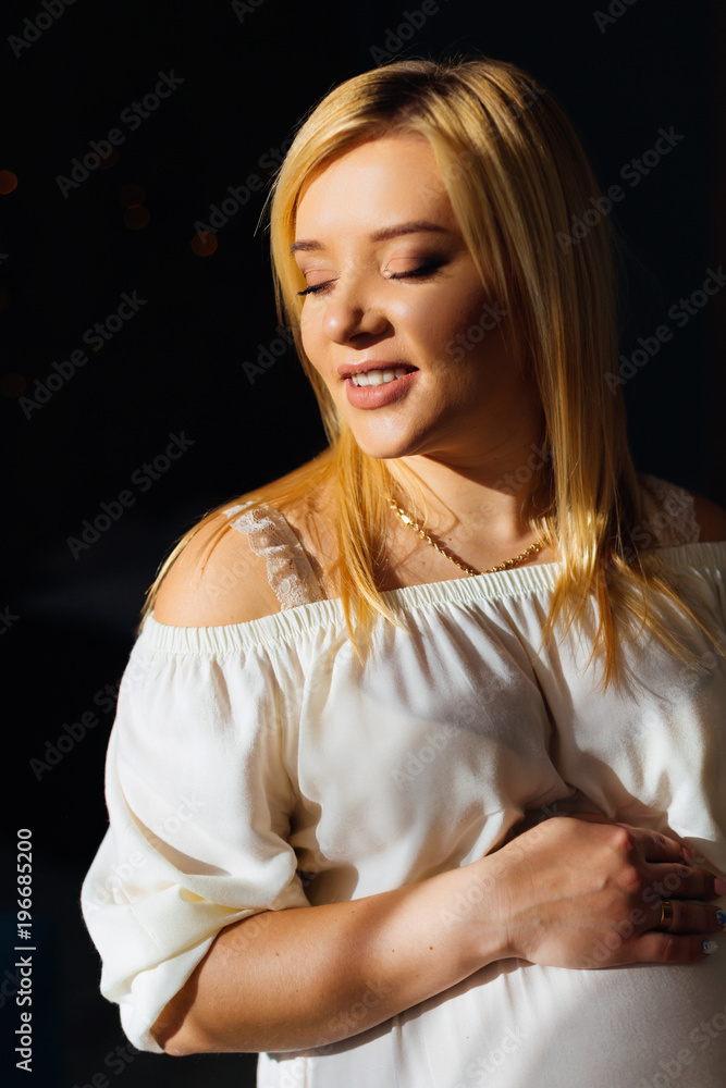 A pregnant woman with a beautiful make-up holds her hand on her round belly A pregnant woman with a beautiful make-up holds her hand on her round belly