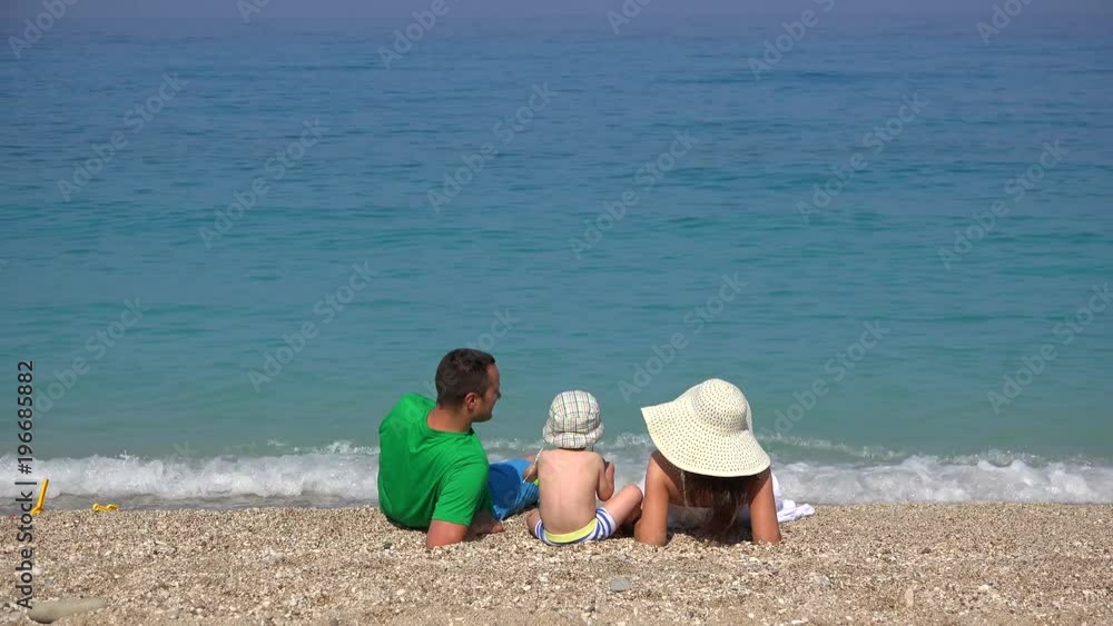 Family, young parents and little child resting on beach, turquoise sea waving 4K Family, young parents and little child resting on beach, turquoise sea waving 4K
