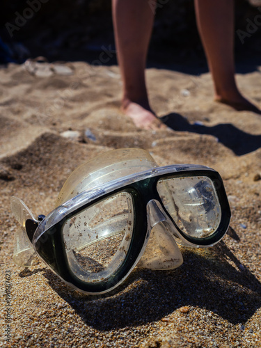 A mask left on the beach and two women legs off focus