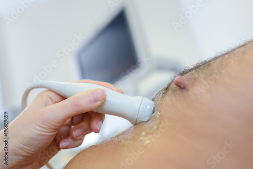 doctor placing ultrasound probe on male patients chest