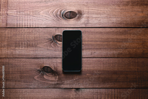 Top view of a modern smartphone with large screen on vintage wooden table. Blank empty display. Mock up