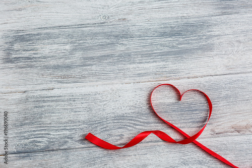 red ribbon in the shape of the heart, background with hearts, concept of the day of the holy valentine