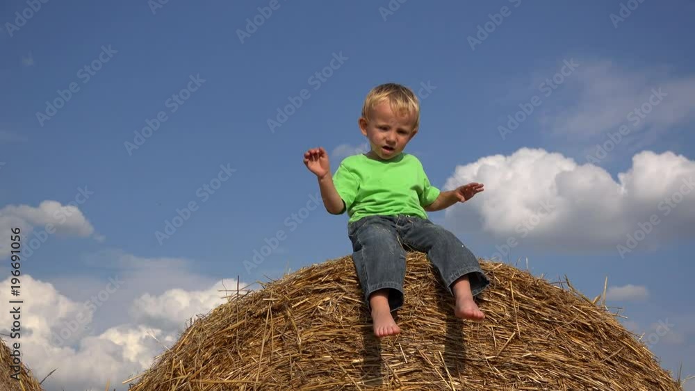 Lovely little boy sing and dance on haystack, enjoy the countryside summer Lovely little boy sing and dance on haystack, enjoy the countryside summer