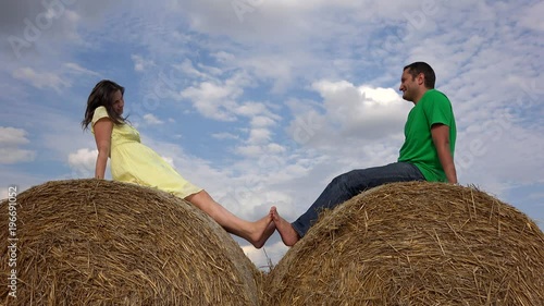 Couple in love on haystack touch bare feet, playing with oles close sky photo