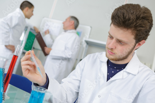 young man lab worker holding up test tubes