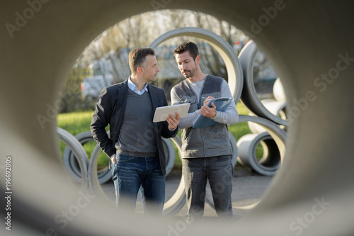Konstfotografi workers next to concrete sewer pipes