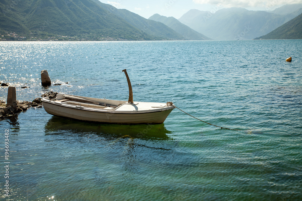 Empty parked boat on the clear transparent water of turquoise color on the lake in the mountains