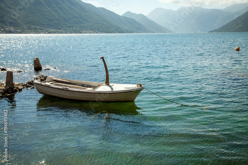 Empty parked boat on the clear transparent water of turquoise color on the lake in the mountains © Nataliia