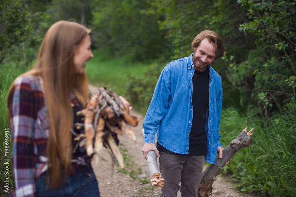 A couple works together to find firewood and build a campfire A couple works together to find firewood and build a campfire