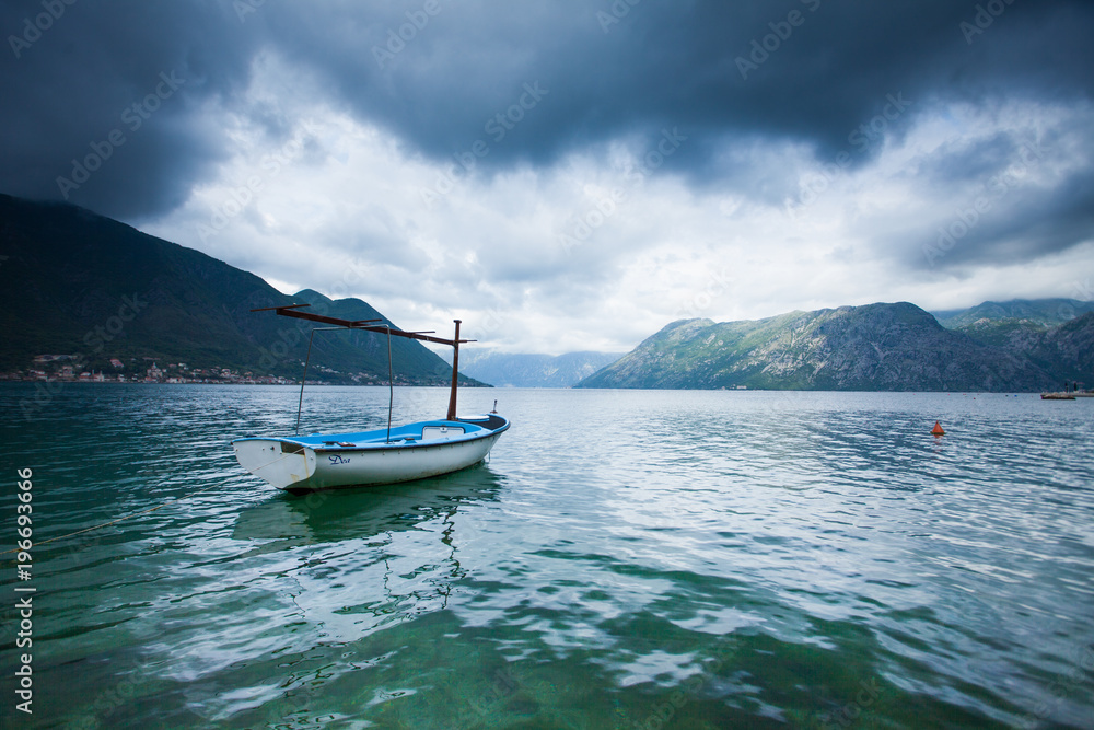 lonely white blue boat is parked on the lake between the mountains
