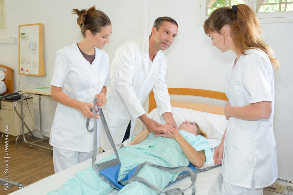 Obraz premium Doctor showing student nurses how to lift patient