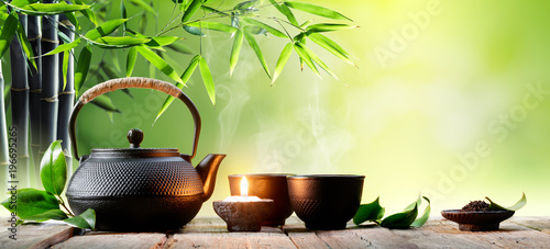Black Iron Asian Teapot and Cups With Green Tea Leaves 