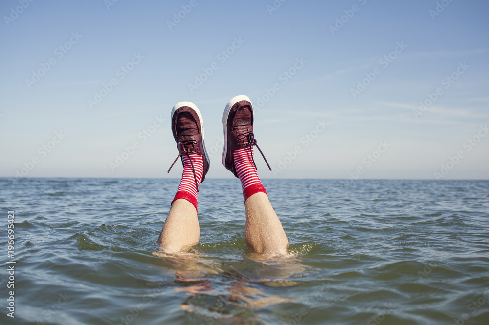 Legs sticking out of the water. Wet shoes and socks Stock-Foto | Adobe Stock