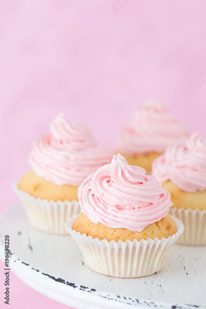 Cupcake decorated with pink buttercream on pastel pink background.