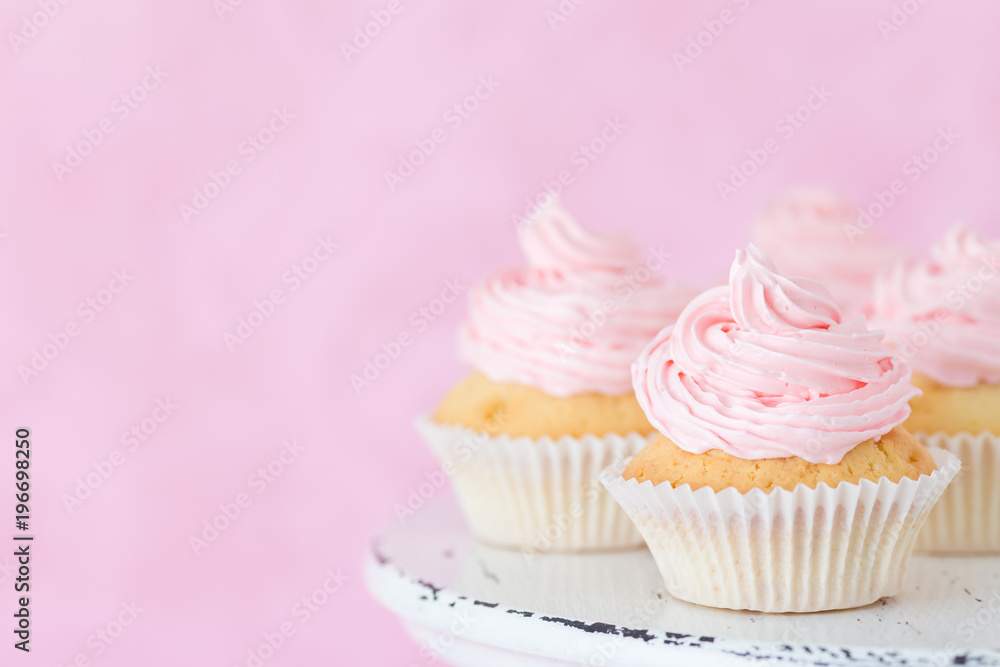 Cupcake decorated with pink buttercream on shabby shic stand on pastel beautiful pink background.
