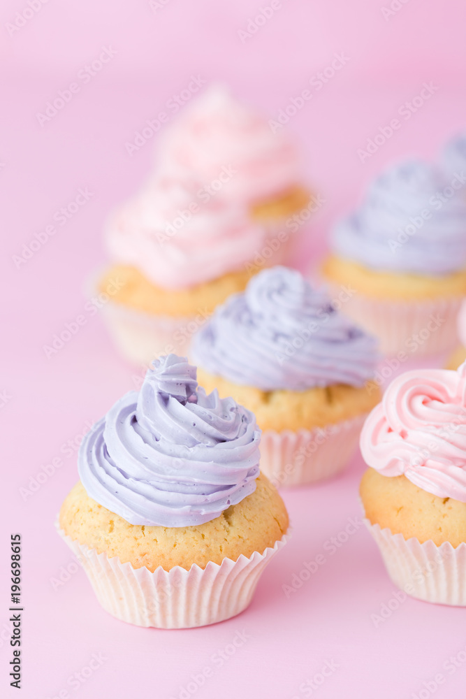 Cupcakes with tender violet and pink buttercream standing on pastel pink background.