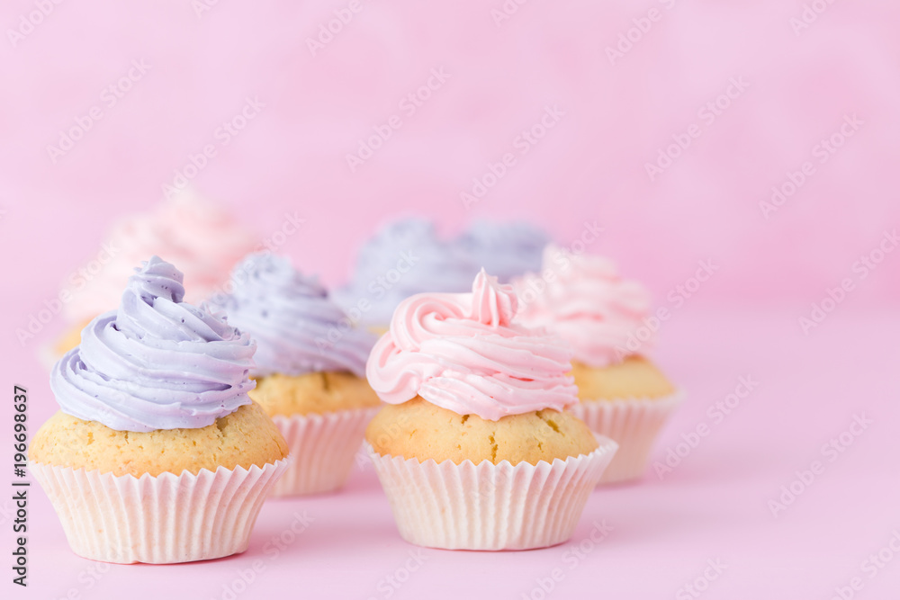 Cupcakes with violet and pink buttercream standing on pastel pink background.