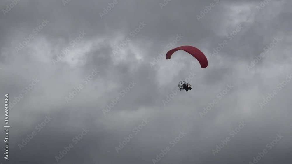 Parachute with motor flying on dark cloudy sky, dangerous flight Parachute with motor flying on dark cloudy sky, dangerous flight