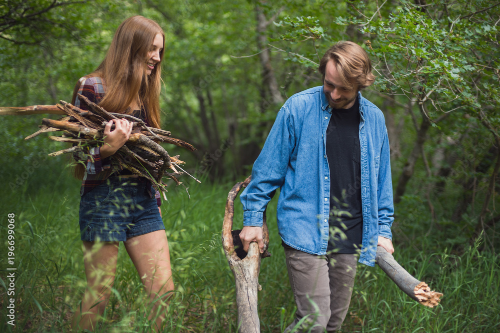 A couple works together to find firewood and build a campfire A couple works together to find firewood and build a campfire