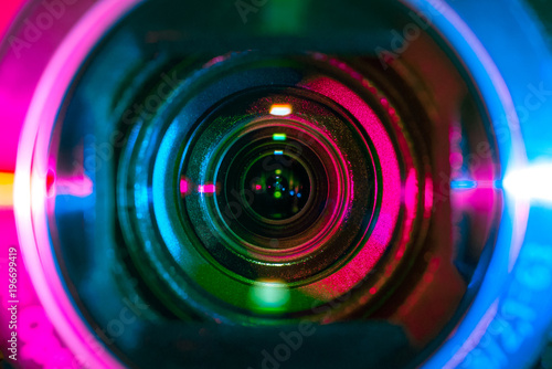 Video camera lens lit by pink or purple and blue neon light