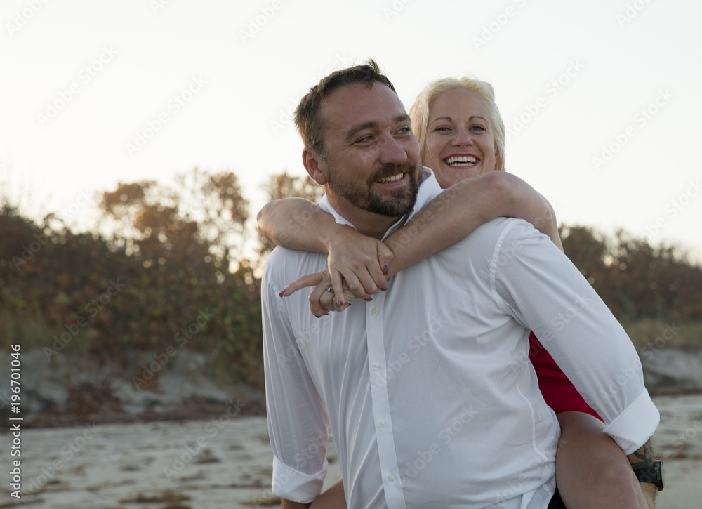 happy couple playing on the beach at sunset happy couple playing on the beach at sunset
