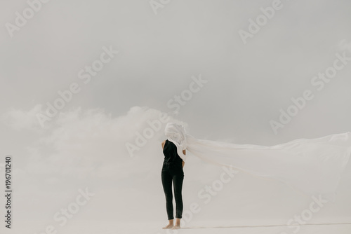 Contrast of woman wearing black with white fabric hiding her face in the minimal landscape photo