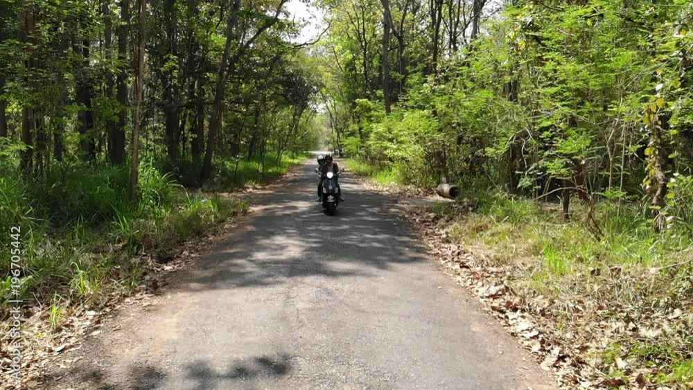 Slow motion Couple riding their scooter through forest. Slow motion Couple riding their scooter through forest.